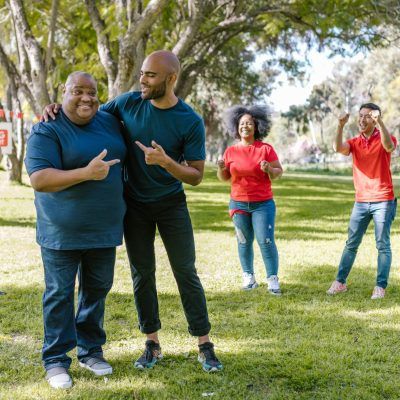 Group of adults engaging in fun team building activities in a sunny park, showcasing teamwork and diversity.
